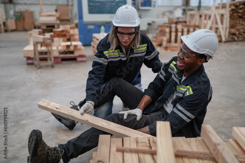 Foreman injured from accident lying on floor crying with pain in warehouse. Female worker emergency help male colleague who falling down get physical injury in workplace. Risk, dangerous in workplace © Nassorn