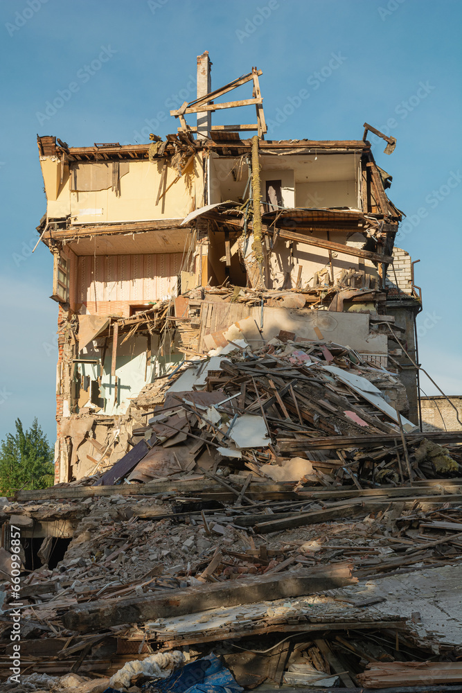 Destroyed residental building with broken apartments and a pile of construction debris. House damaged by terrorist attack, war or earthquake background
