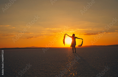 Young ballerina walking on the lake at sunset