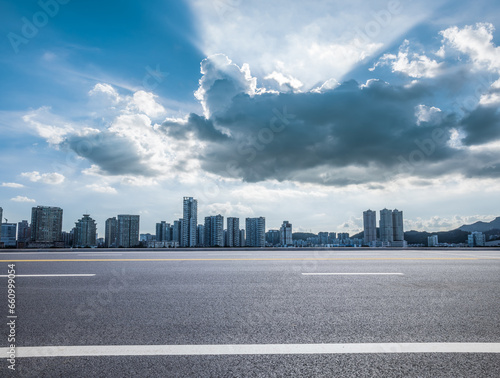 Asphalt road and city buildings with sky clouds background