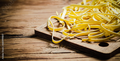 Homemade pasta tagliatelle. On wooden table.