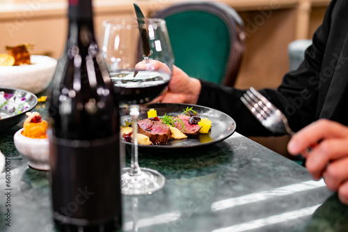 man  hands eats meat with red wine in a restaurant