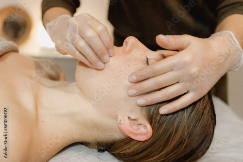 buccal facial massage, close-up, cosmetologist makes woman a procedure on a massage table in a spa salon