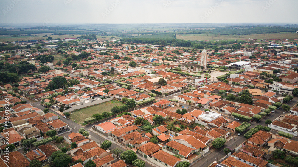 Cidade de Palestina, localizada no interior do Brasil vista de cima em dia levemente nublado, pegando a praça da igreja como referência e mostrando toda a cidade pelo ponto de vista de drone