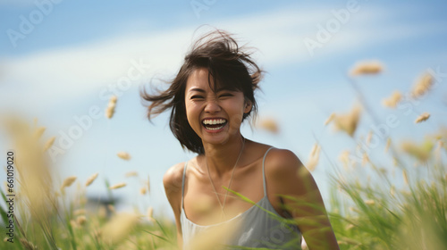 Happy asian woman in field of grass. Laughing and enjoying moment.