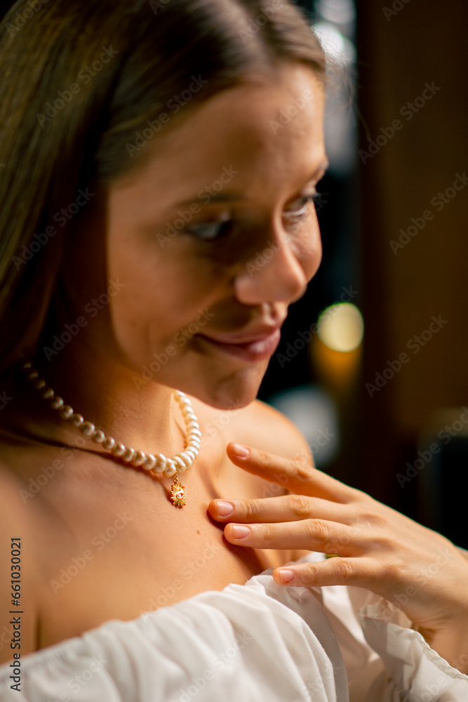 close-up of the neck and collarbones of a girl trying on a beautiful pearl necklace beauty craft jewelry