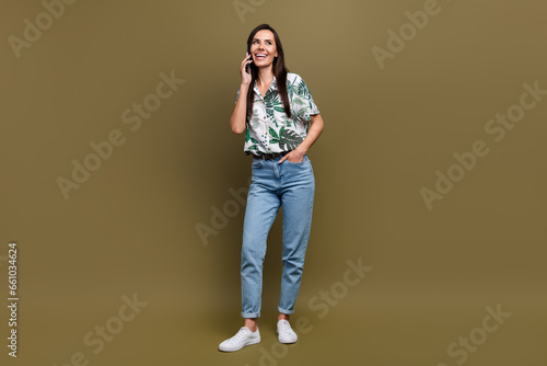 Full size photo of cheerful lovely girl good mood talk communicate telephone isolated on brown color background