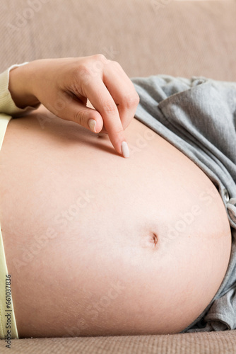 pregnant woman sitting in bed and touching her belly at home. pregnancy expectation concept.