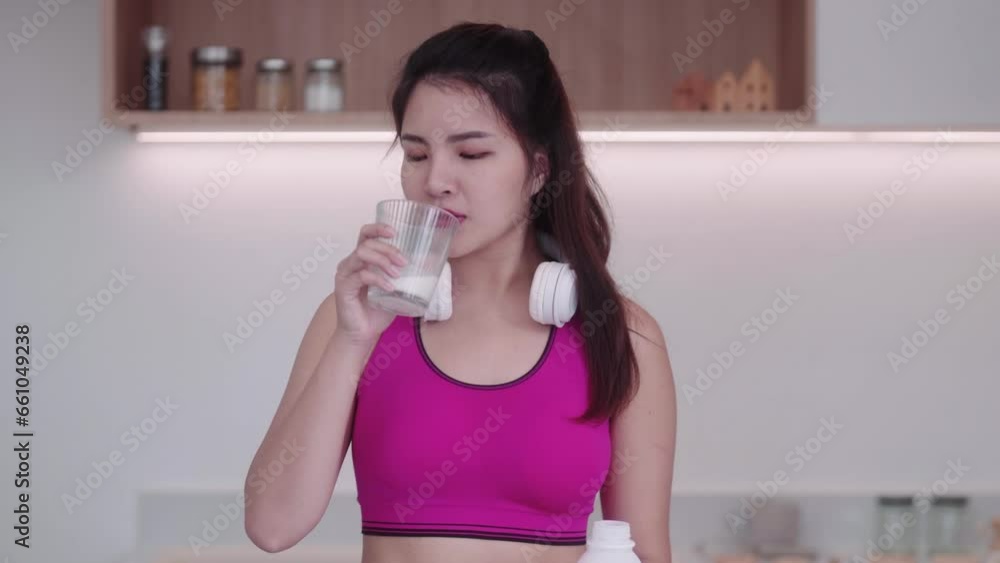 Healthy sporty young Asian woman in sportswear holding and drinking pure milk or whey healthy diet in kitchen at home, Healthcare and weight loss concept Healthy sporty young Asian woman in sportswear holding and drinking pure milk or whey healthy diet in kitchen at home, Healthcare and weight loss concept
