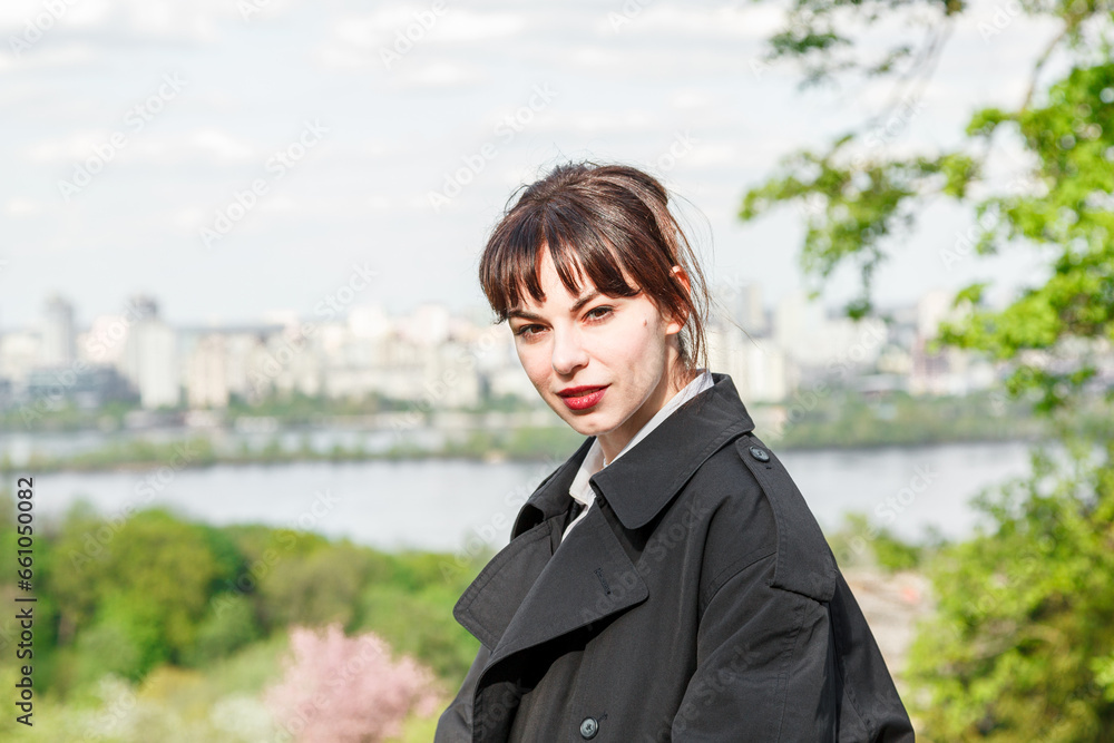 A beautiful girl drinks coffee at the table, in a raincoat, in a white shirt, in black trousers with suspenders A beautiful girl drinks coffee at the table, in a raincoat, in a white shirt, in black trousers with suspenders