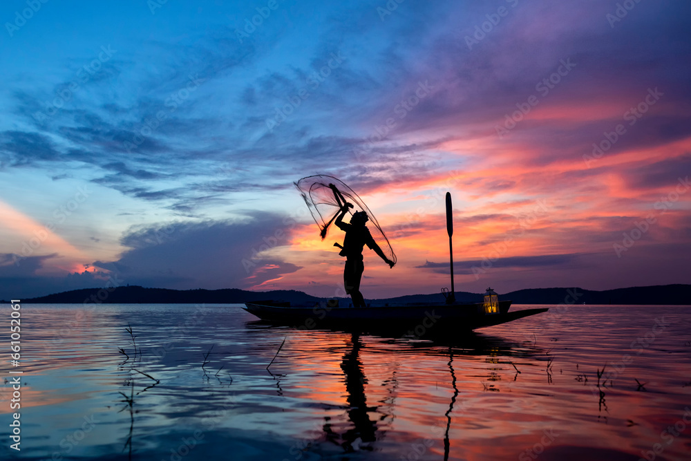 Silhouette of middle aged Asian fisherman while throwing fishing net from boat on lake in the morning. Thailand