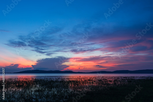 Beautiful colors of clouds, sky and sunrise on a serene lake in the background.