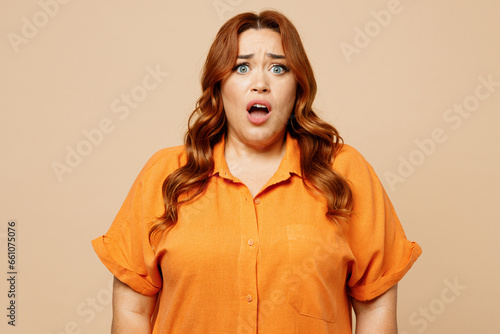 Canvas Print Young sad shocked ginger chubby overweight woman she wear orange shirt casual clothes look camera with opened mouth isolated on plain pastel light beige background studio portrait