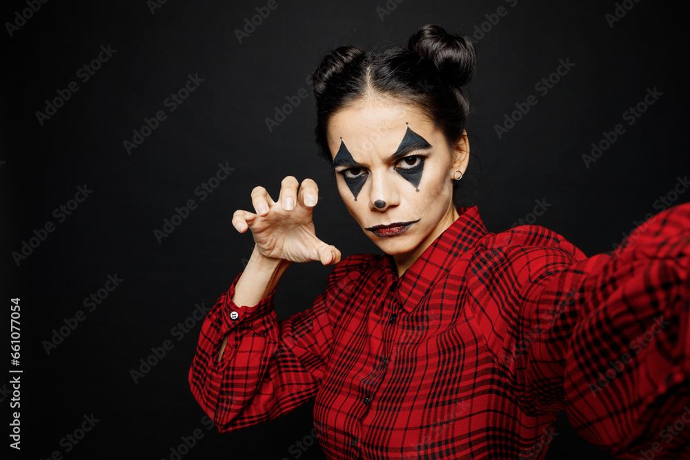 Young woman with Halloween makeup face art mask wears clown costume red dress do creepy selfie shot pov mobile cell phone isolated on plain solid black background studio. Scary holiday party concept. Young woman with Halloween makeup face art mask wears clown costume red dress do creepy selfie shot pov mobile cell phone isolated on plain solid black background studio. Scary holiday party concept.