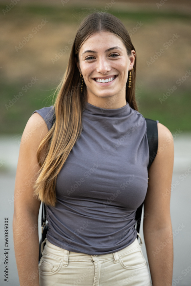 Beautiful cheerful young lady looking at camera standing outside.Joyful blond woman staring at camera in the street.