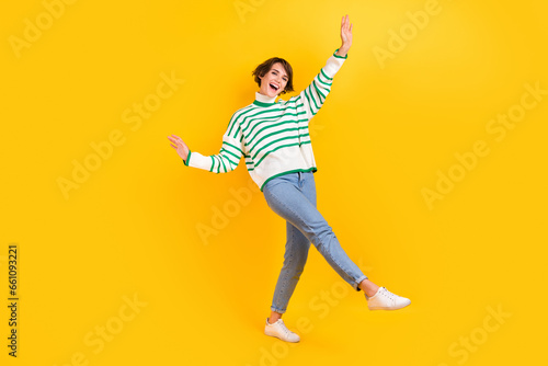 Full body photo of attractive careless girl wear casual stylish striped pullover with jeans party event isolated on yellow color background