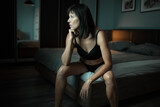 Brunette woman in black lingerie resting in bedroom at home