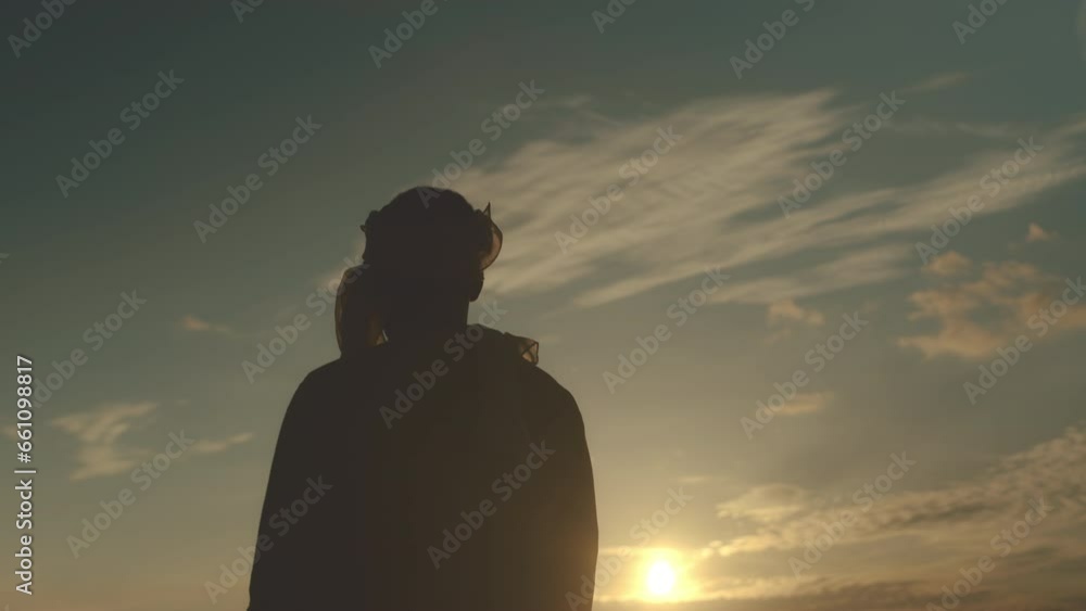 Back view medium slowmo of unrecognizable man in headscarf walking on sand in desert at golden hour Back view medium slowmo of unrecognizable man in headscarf walking on sand in desert at golden hour