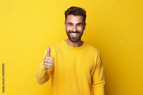 young man happily keeping thumbs up on isolated yellow background copy space