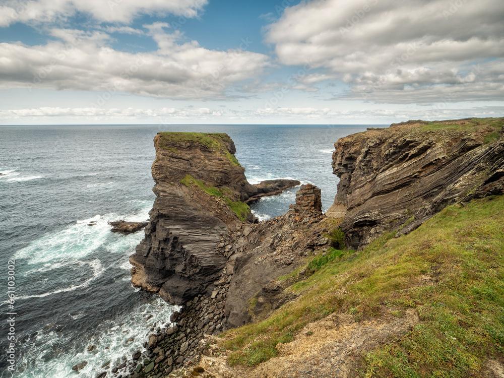 Stunning scene with cliffs, rough stone island, ocean and blue cloudy sky. Ireland, Kilkee area. Travel, tourism and sightseeing concept. Irish landscape and coastline. Beautiful nature view.