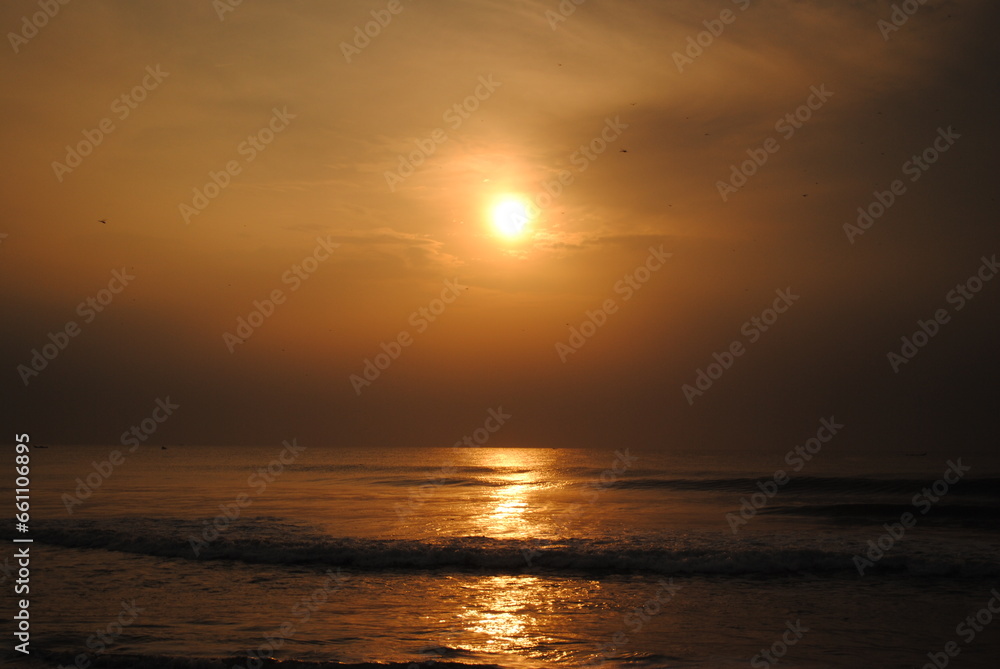 Bright sun coming out on a early morning displaying a golden cloth on the sea captured with selective focus in Chennai