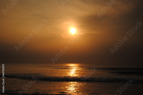 Bright sun coming out on a early morning displaying a golden cloth on the sea captured with selective focus in Chennai