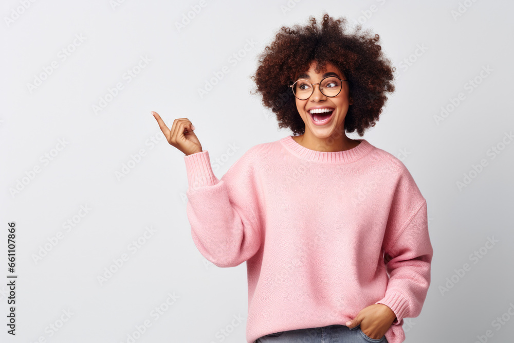 Young African American Woman in Glasses, Pointing Up, Pink Sweater, white background Young African American Woman in Glasses, Pointing Up, Pink Sweater, white background