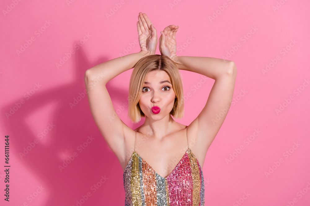 Portrait of gorgeous positive girl with plump lips dressed stylish clothes hold hands like hare ears isolated on pink color background Portrait of gorgeous positive girl with plump lips dressed stylish clothes hold hands like hare ears isolated on pink color background
