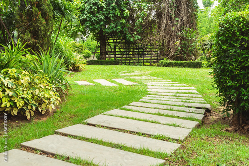 Garden landscape design with pathway intersecting bright green lawns and shrubs white sheet walkway in the garden.