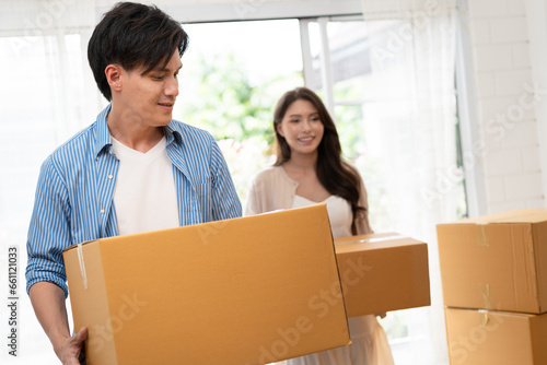 Happy Asia couple holding cardboard box with walk in new home 