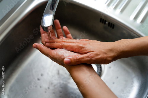 Unrecognizable hands washing in a kitchen sink