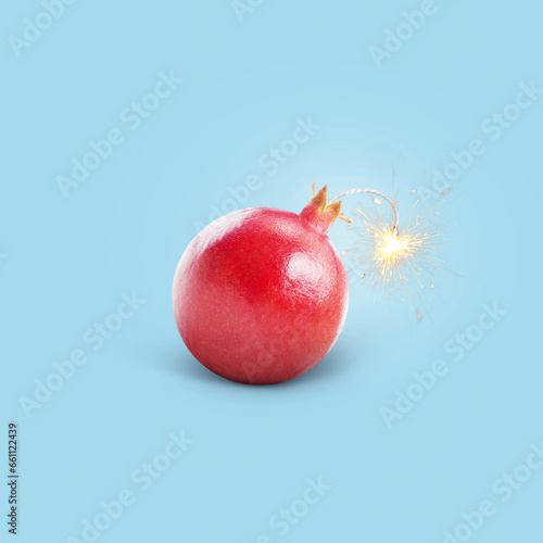 Creative juicy bomb pomegranate with a wick with sparks burning on a blue background, concept. Vitamins and healthy eating, creative idea. Diet and strengthening blood vessels, immunity
