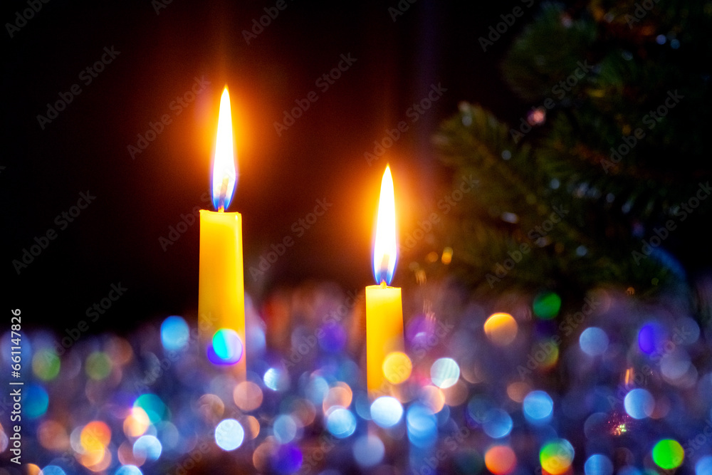 Two candles burning on a dark background with bokeh during Christmas and New Year celebrations Two candles burning on a dark background with bokeh during Christmas and New Year celebrations