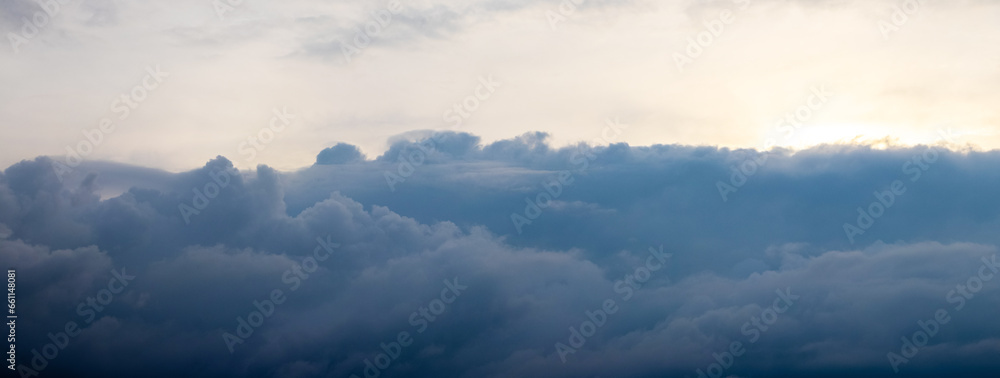 Dark storm clouds on the background of the sky illuminated by the evening sun