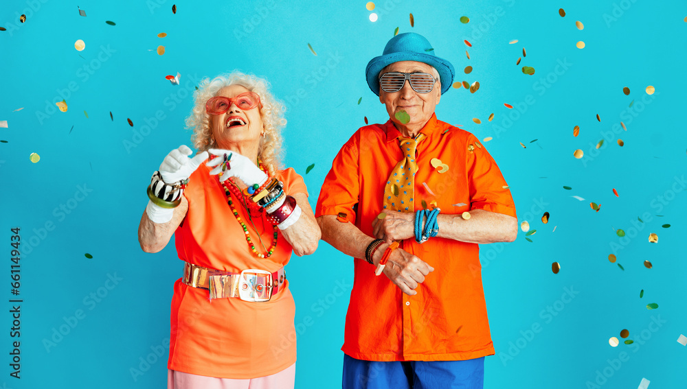 Obraz premium Beautiful senior old couple wearing fancy party clothes acting in studio on a colored background. Conceptual image about third age and seniority, old people feeling young inside.