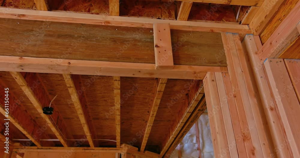 An interior view newly constructed house showing its unfinished construction wooden framing beams An interior view newly constructed house showing its unfinished construction wooden framing beams