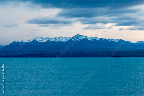 Photograph of Lake Pukaki early in the morning on a cloudy day with snow-capped mountains in the background on the South Island of New Zealand