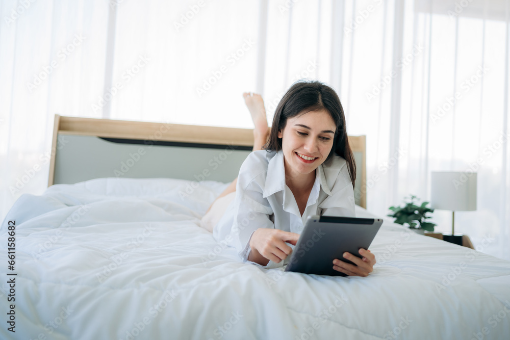 Young Woman Waking Up and play phone in Cozy Bedroom at Home. Beautiful Girl Smiling and Relaxing in Bed after Waking Up. Young Woman Waking Up and play phone in Cozy Bedroom at Home. Beautiful Girl Smiling and Relaxing in Bed after Waking Up.