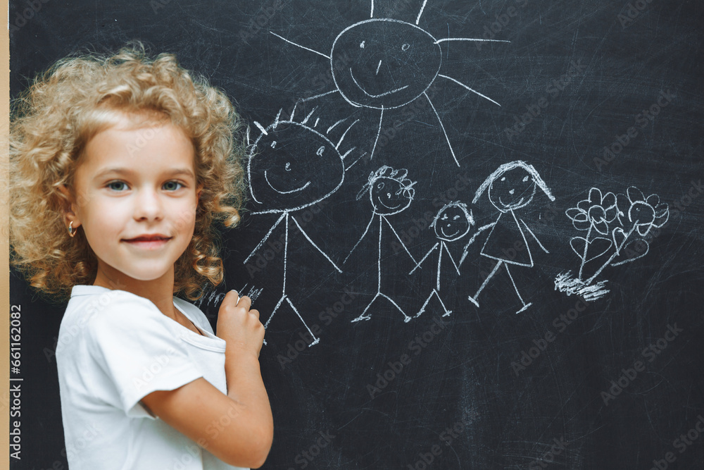 Little girl draws a family on a chalkboard