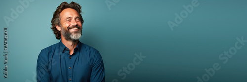 middle age man wearing a blue shirt looking to the side smiling in against a green background. Banner design with space for text