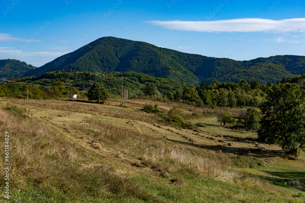 Autumn landscape of nature on a sunny autumn day with mowed meadows and hills under the blue sky in the background. Concept of the arrival of autumn and cooler days in nature
