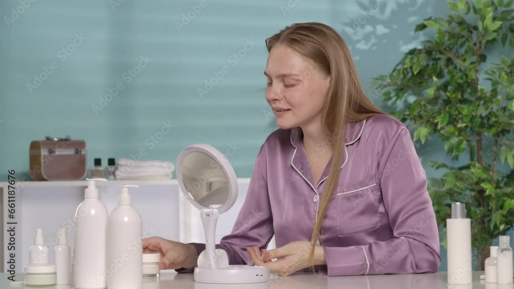 A woman examines her face in a mirror. The woman thinks about it, raises her index finger up, an idea. A woman picks up a jar of cream in her hands, and puts her finger to her lips, a secret. A woman examines her face in a mirror. The woman thinks about it, raises her index finger up, an idea. A woman picks up a jar of cream in her hands, and puts her finger to her lips, a secret.