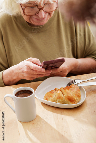 senior woman using her cell phone at breakfast