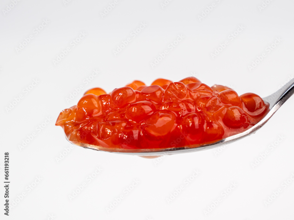 Spoon with red caviar on a white background. Red caviar close-up. Spoon with red caviar on a white background. Red caviar close-up.
