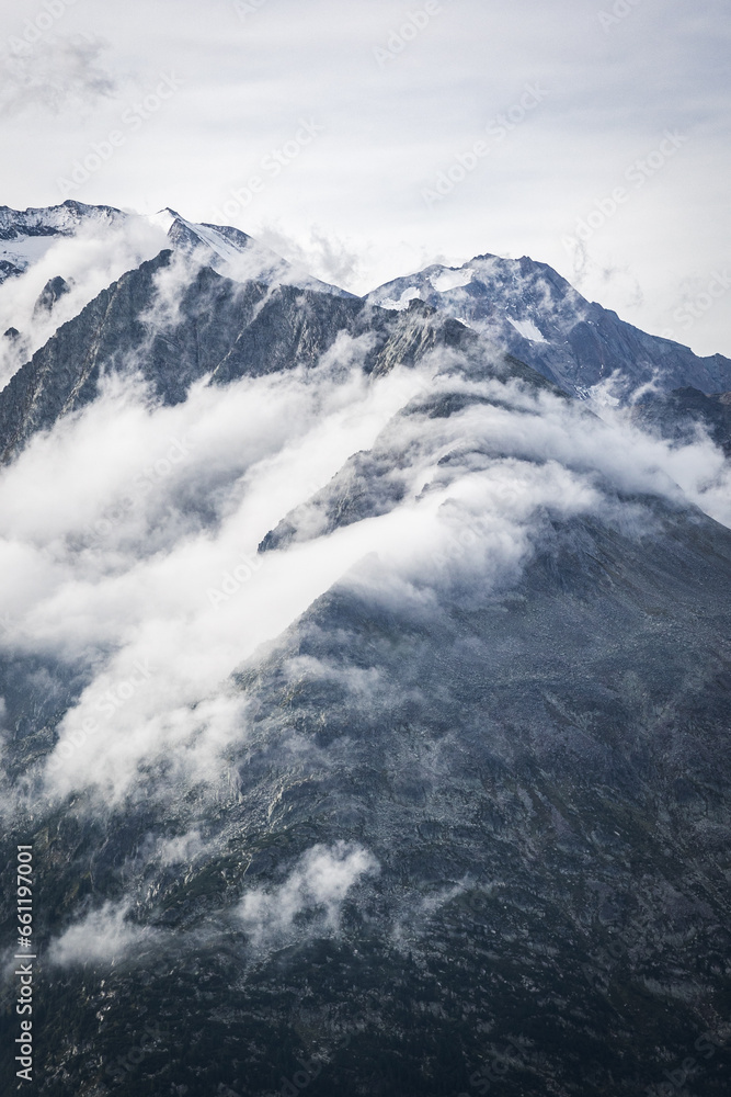 snow covered mountains looking through the fog and clouds 