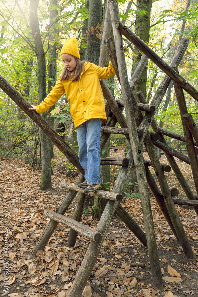 Parkour for children in the park. Obstacle course for children in the autumn park. Teenage girl carefully walks on logs