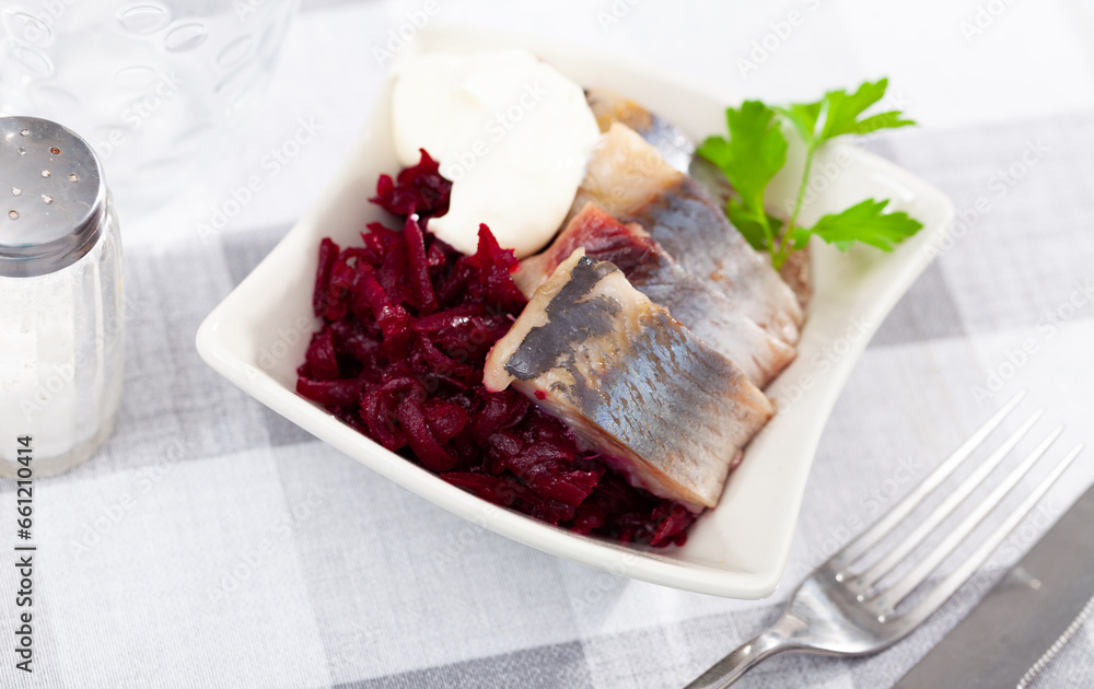 Traditional herring salad with beetroot and parsley in a white plate