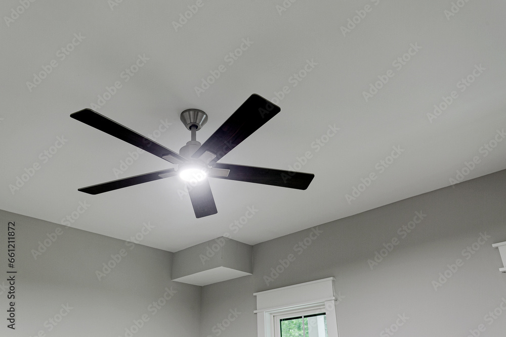 Glowing Ceiling Fan with Wood Arms and Chrome Accents on Clean Ceiling with Copyspace Glowing Ceiling Fan with Wood Arms and Chrome Accents on Clean Ceiling with Copyspace