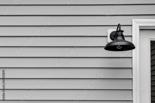 Metal Black Modern Farmhouse Light Sconce on Home Deck Exterior with Grey Siding and Copyspace