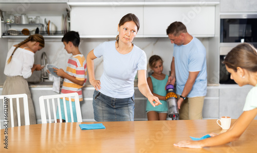 Strict mother tells her daughter how to properly dust off the table